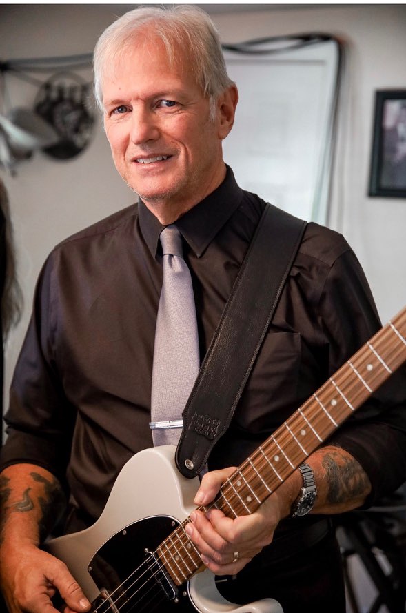 a man in a black shirt is holding an electric guitar