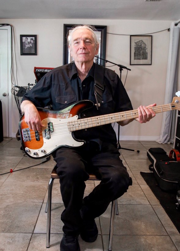an older man sitting on a chair holding a bass