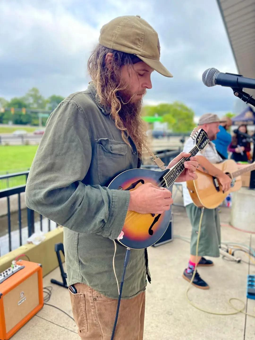 a man with a beard playing a mandolin in front of a microphone