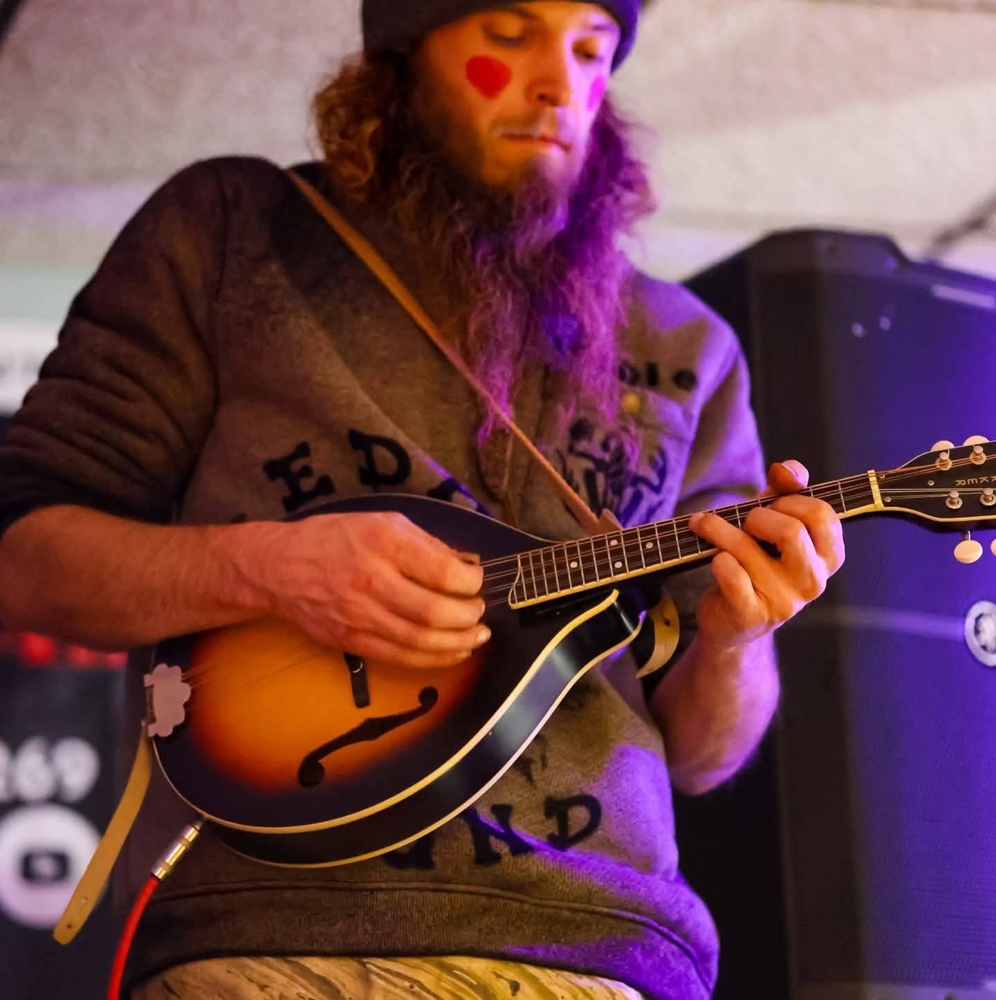a man with a beard playing a mandolin