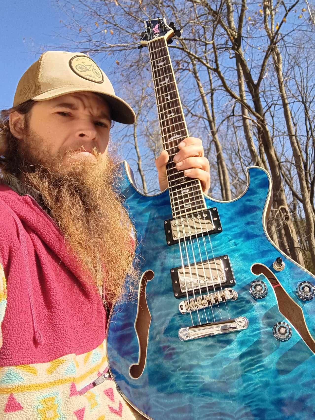 a man with a beard holding a blue electric guitar