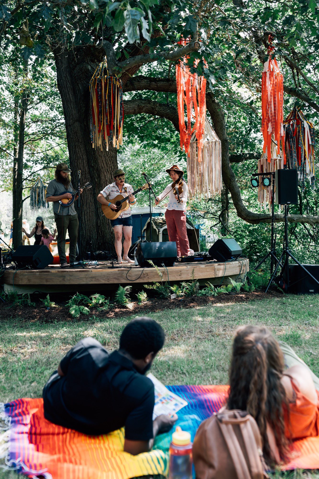 a group of people sitting on a blanket under a tree