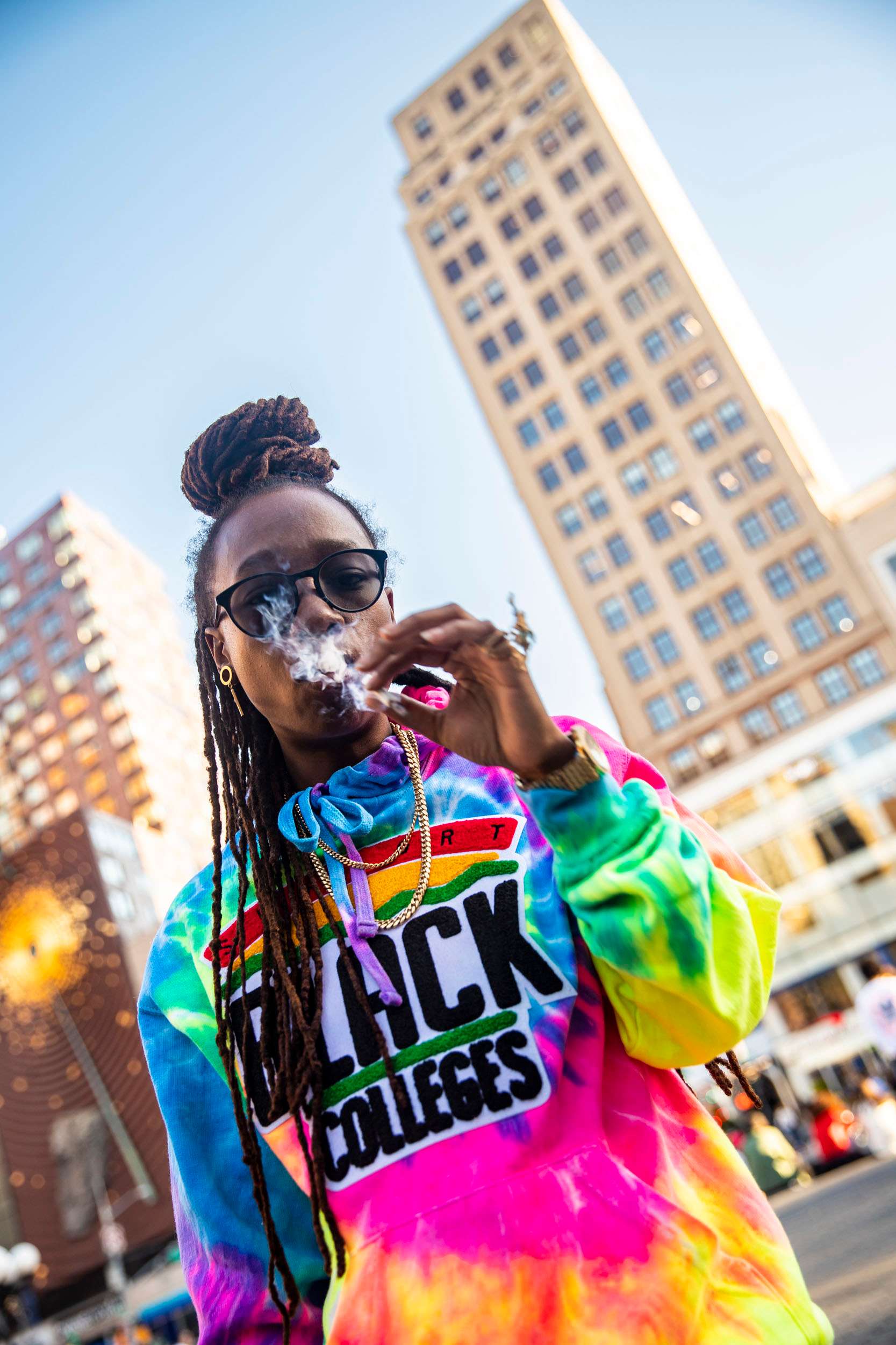 a woman in a colorful hoodie smoking a cigarette