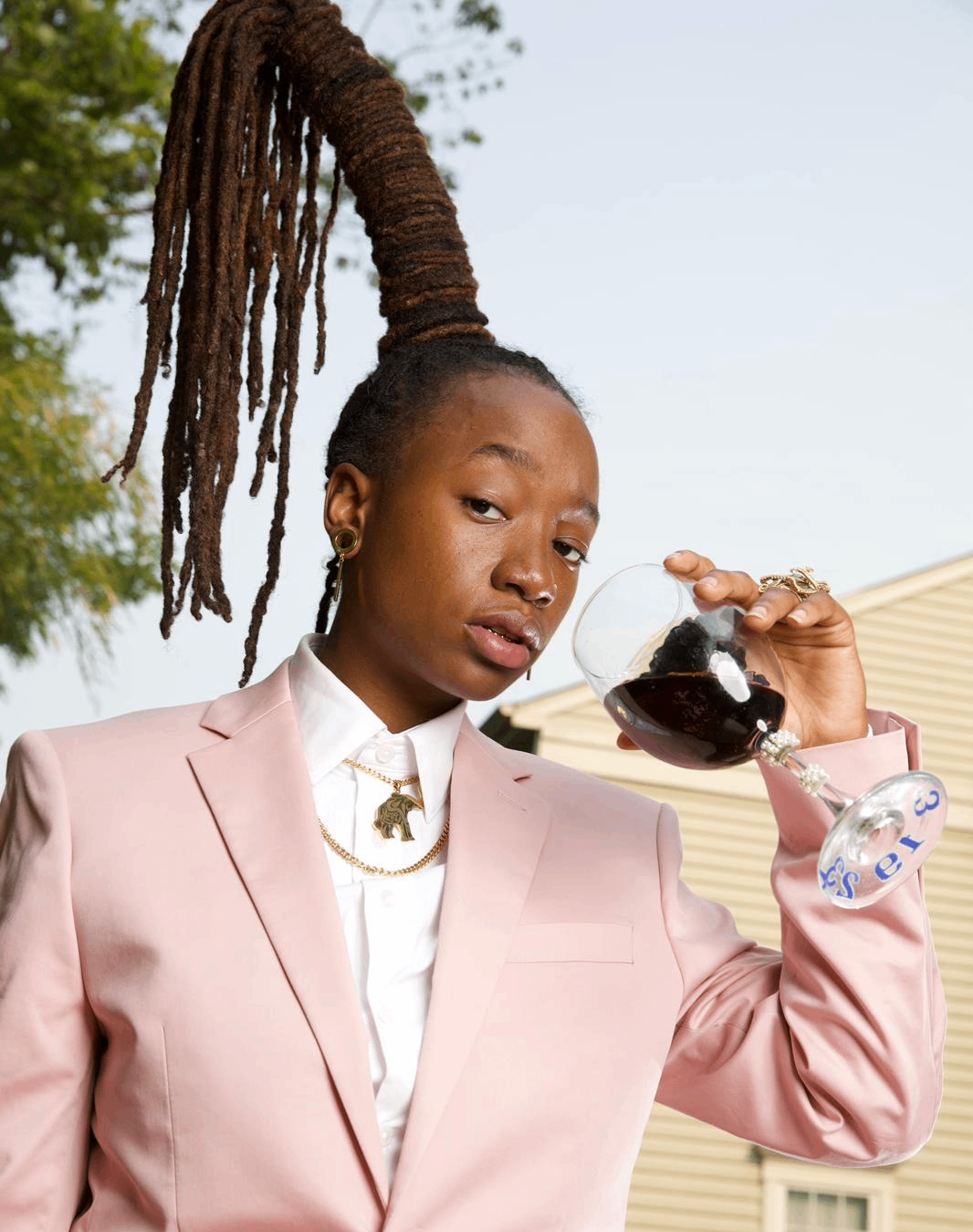 a woman with dreadlocks holding a glass of wine
