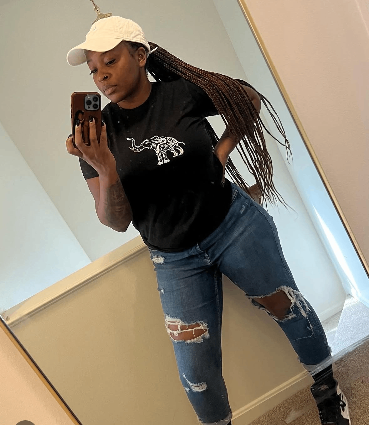 a woman taking a selfie in ripped jeans and a black t - shirt