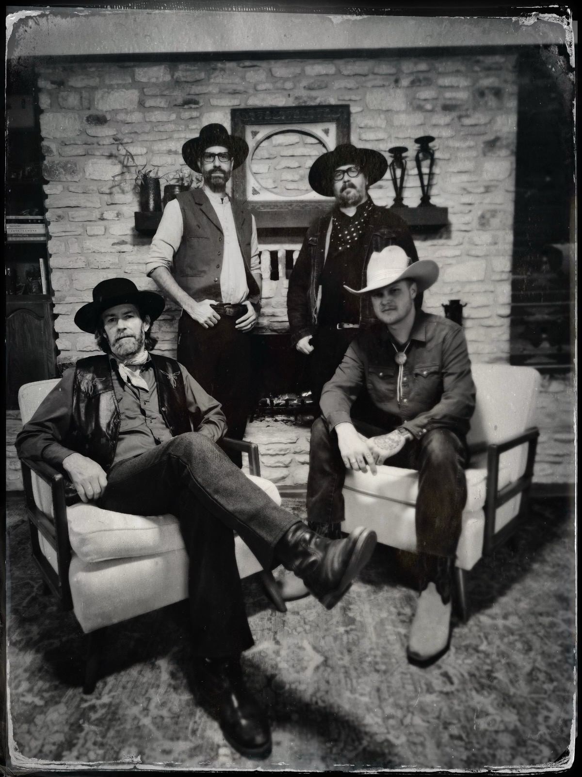 four men in cowboy hats posing in front of a fireplace