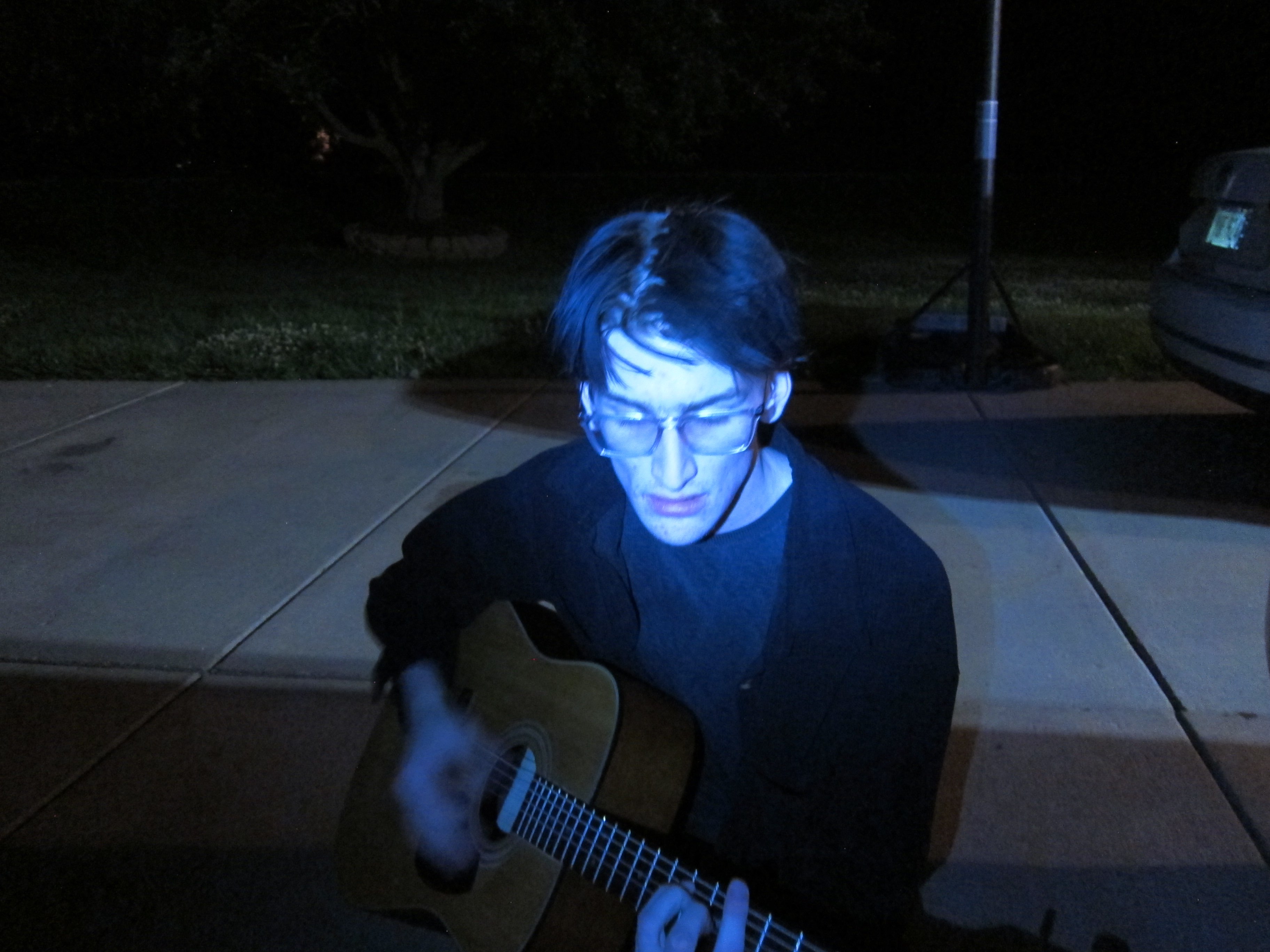 a young man playing an acoustic guitar at night