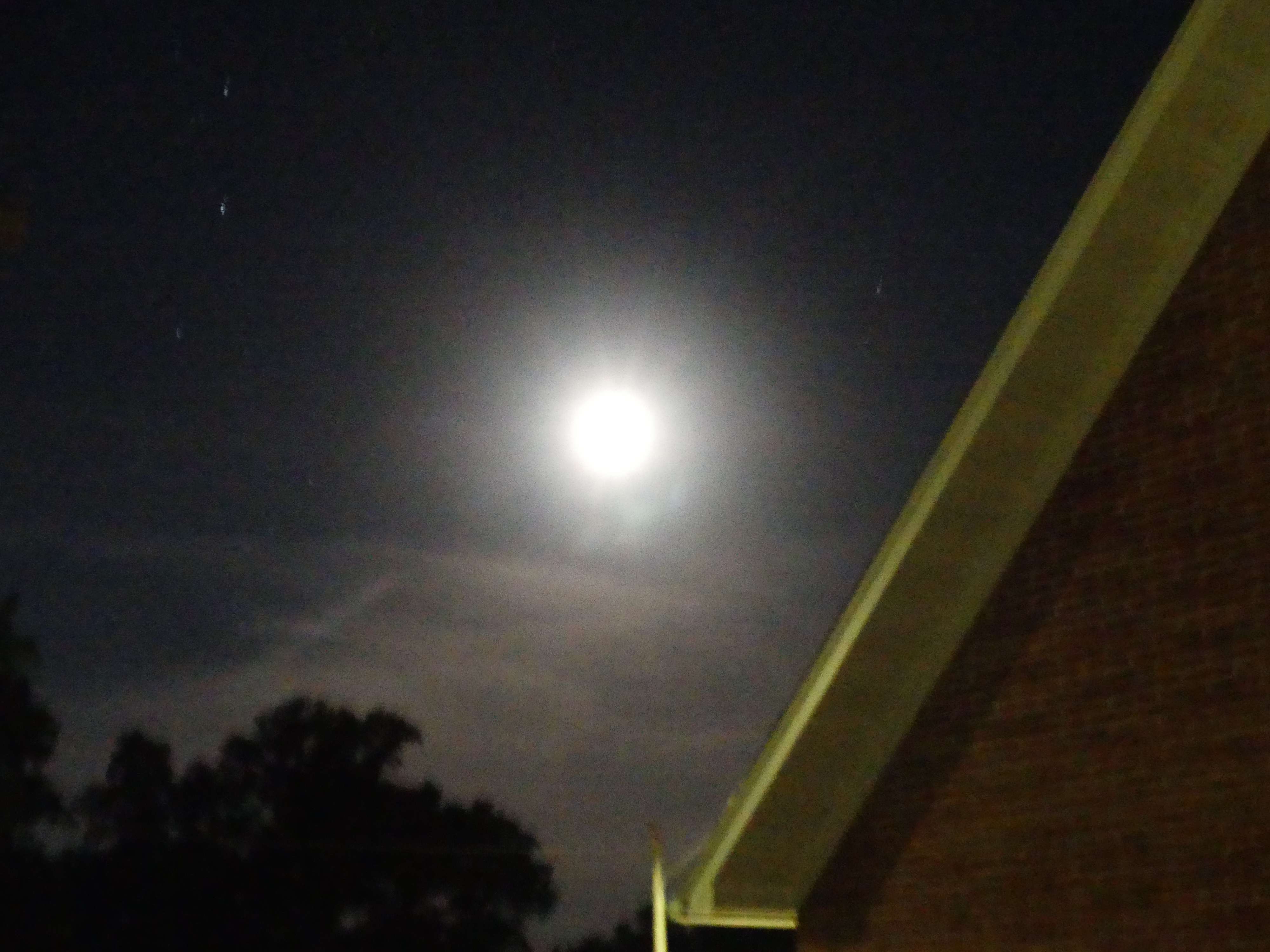a full moon rises over a brick building at night