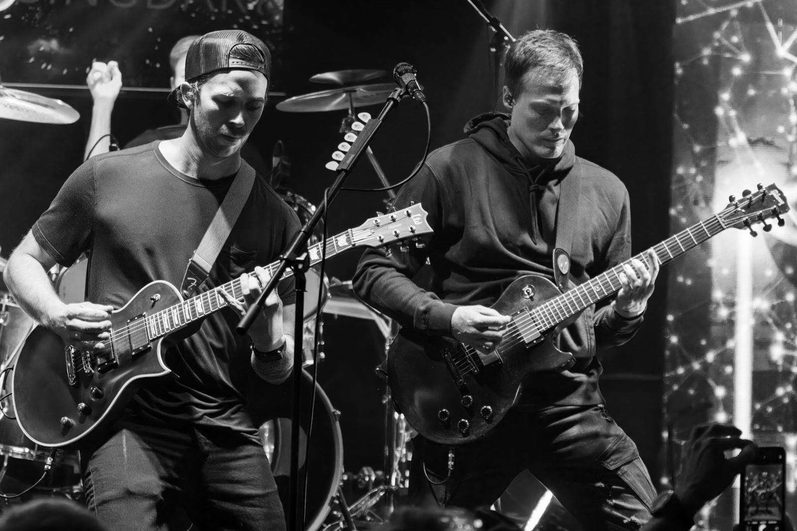 a black and white photo of two men playing guitars on stage