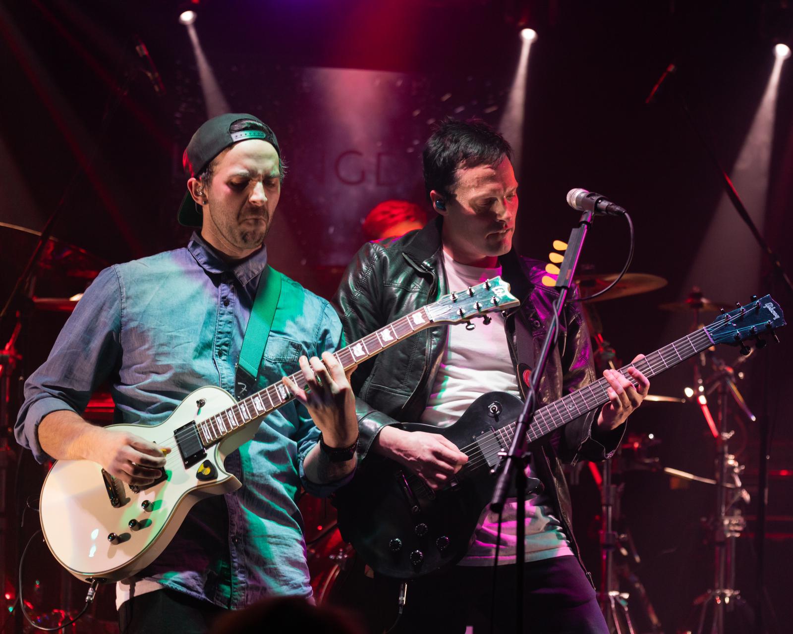 two men playing guitars on stage