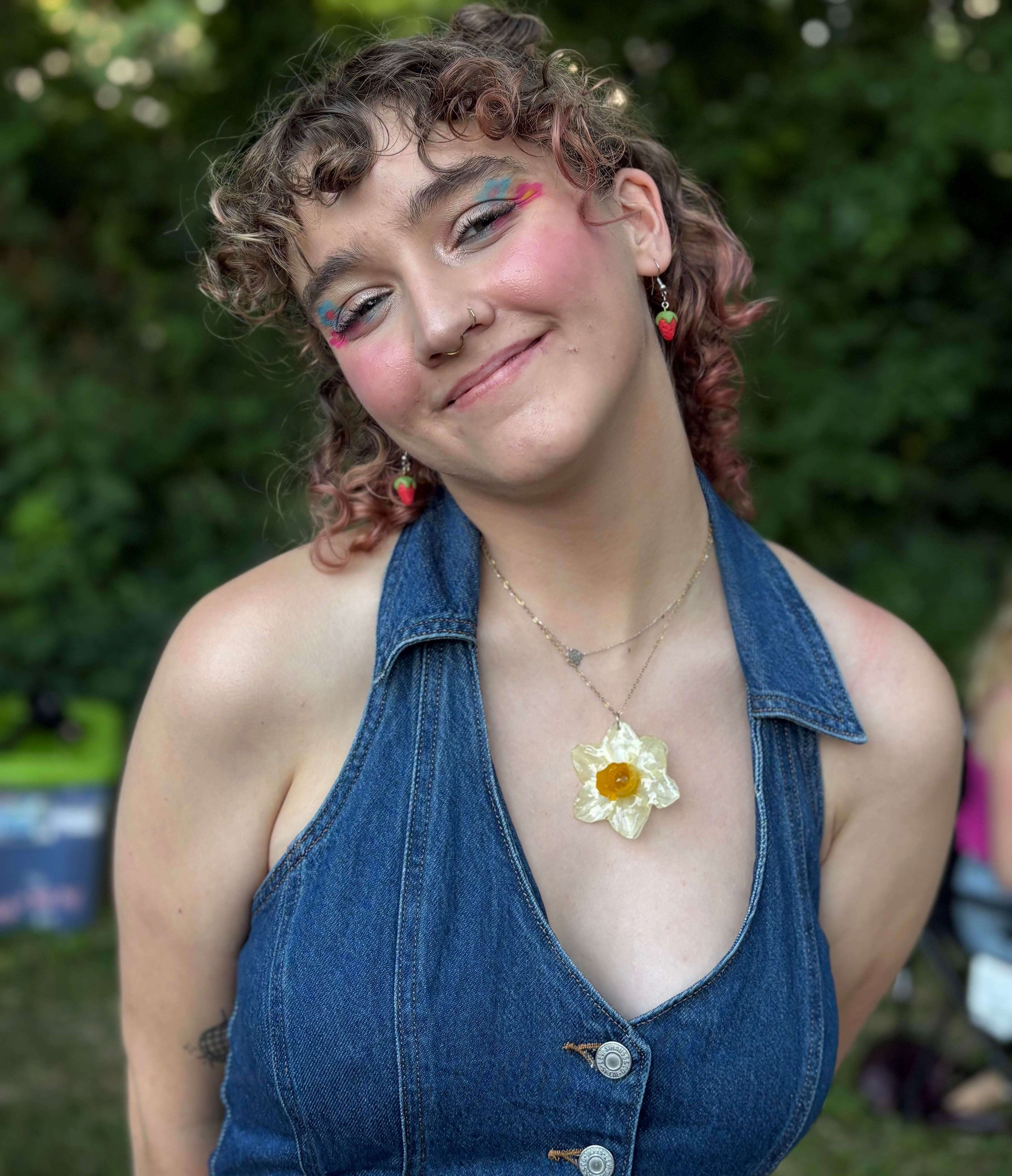 a woman wearing a denim dress with a flower necklace