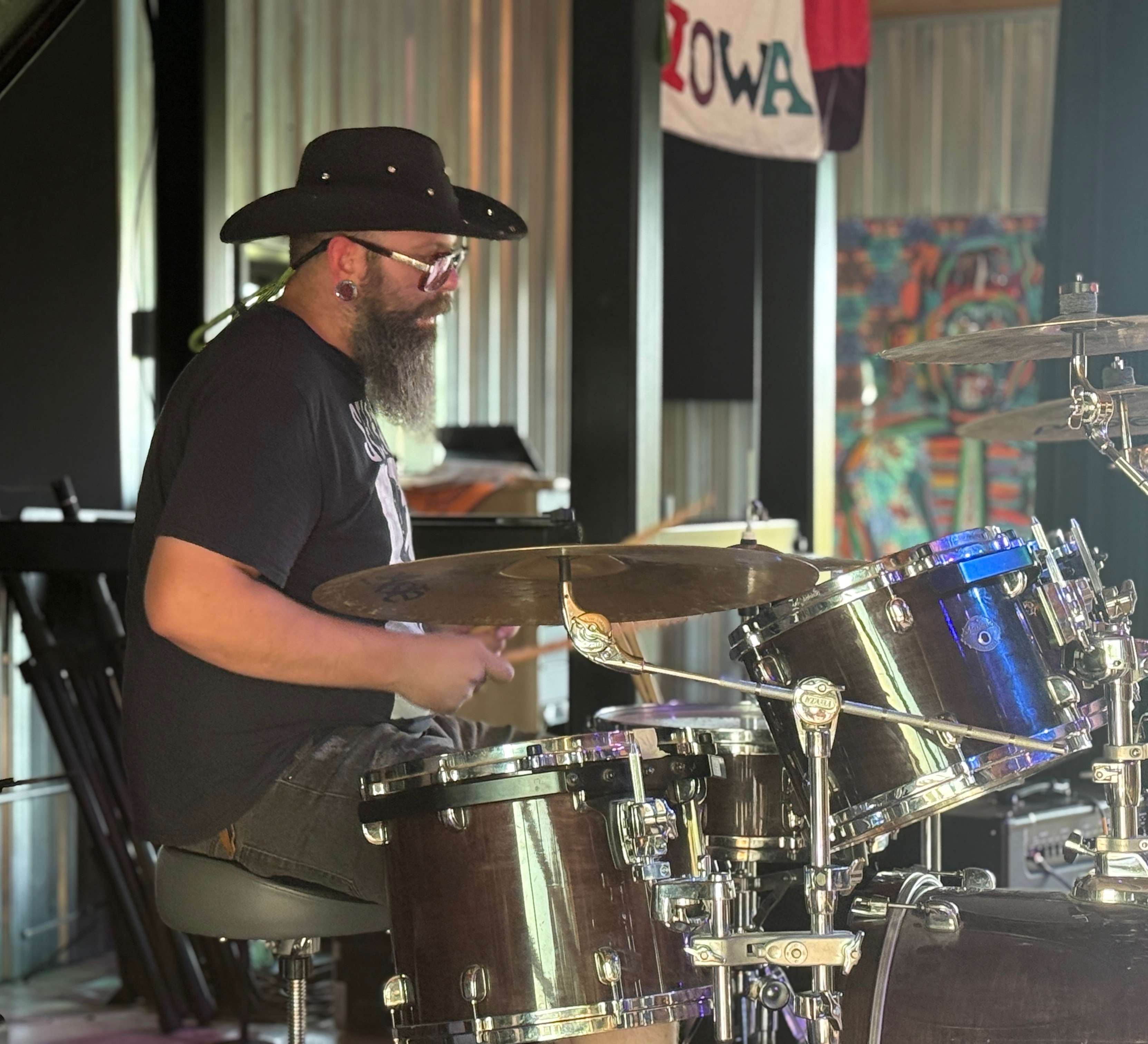 a bearded man in a hat playing drums
