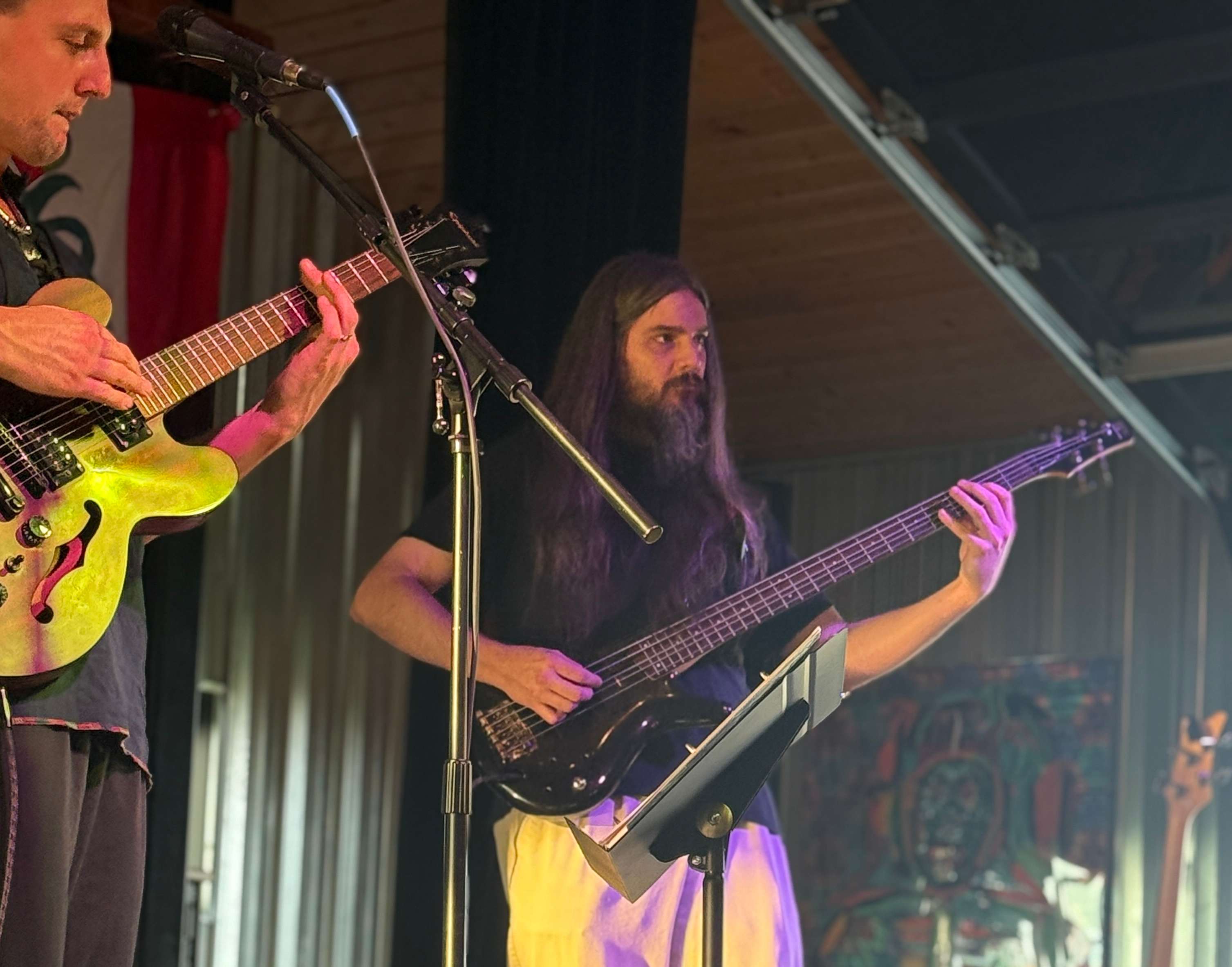 two men playing guitars in front of a microphone