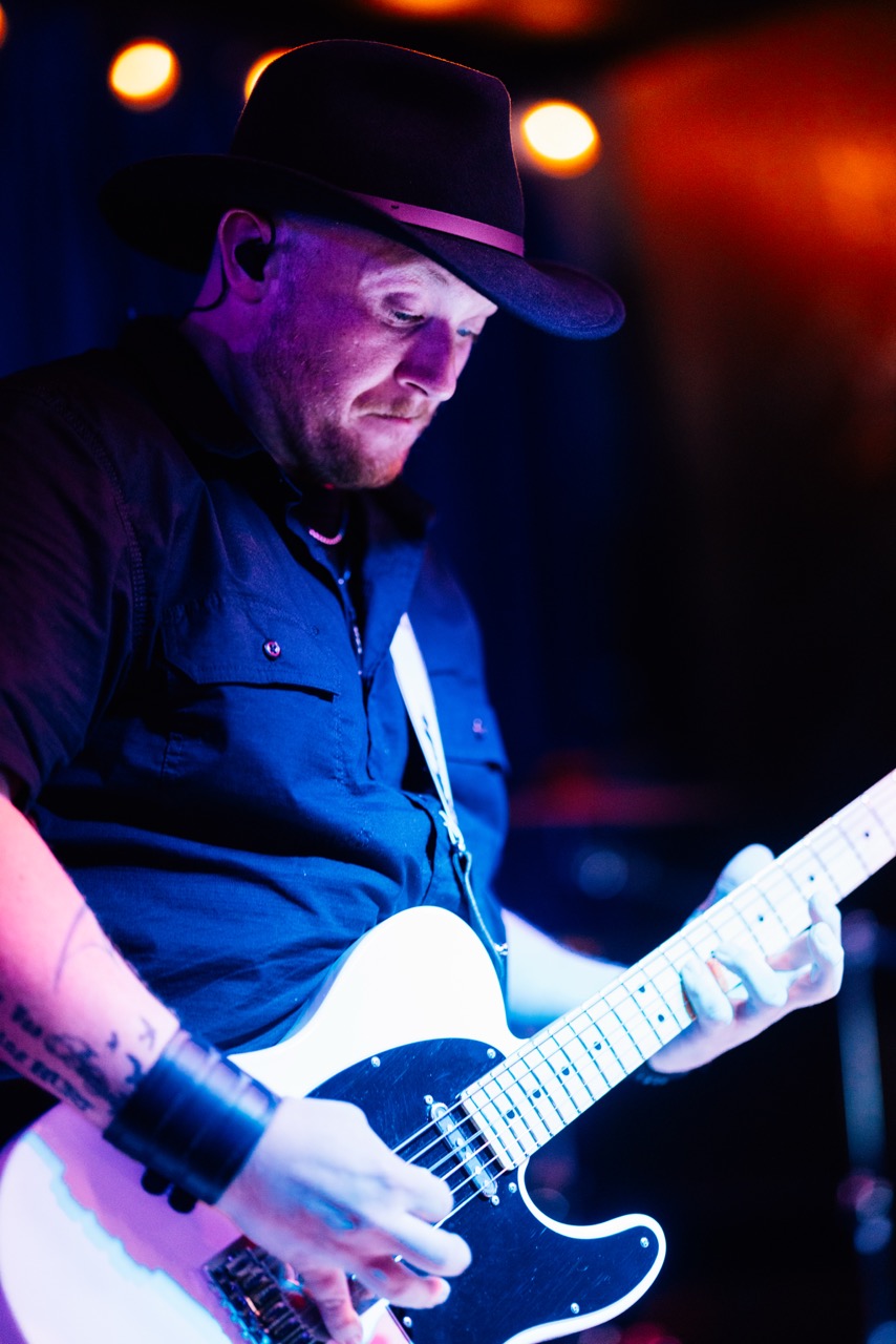 a man in a black hat playing a white guitar