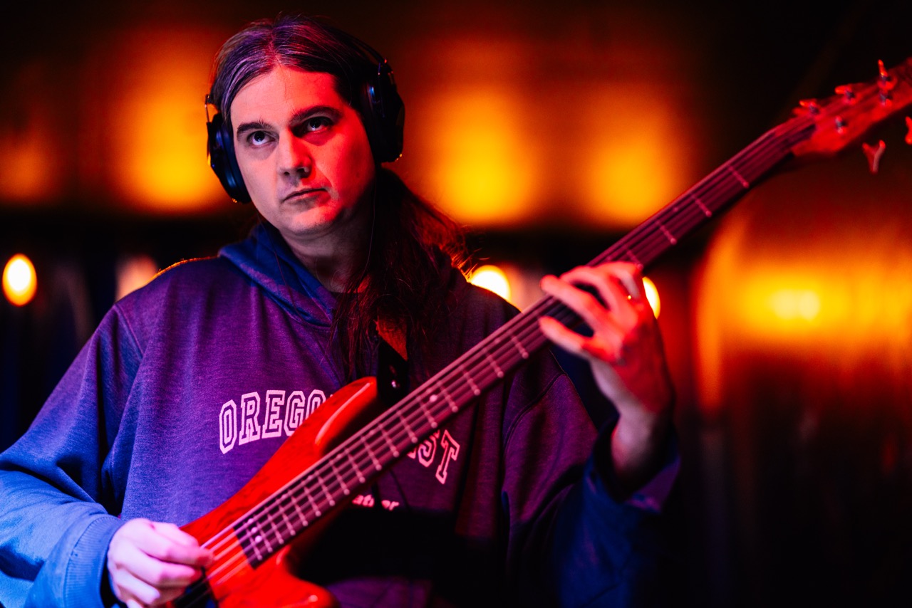 a man with headphones playing a bass in a dark room