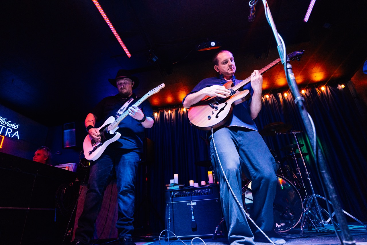 two men playing guitars on stage