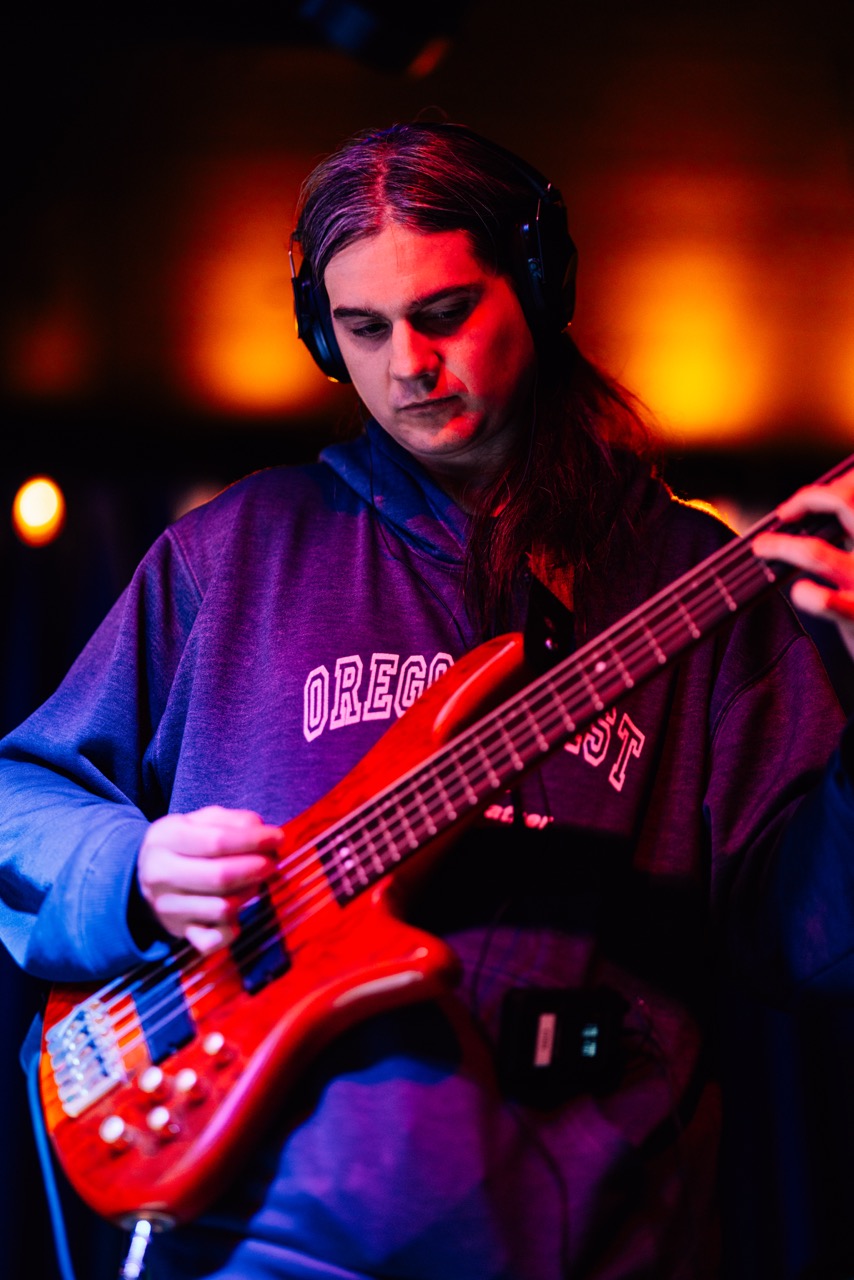 a person playing a red bass in front of a microphone