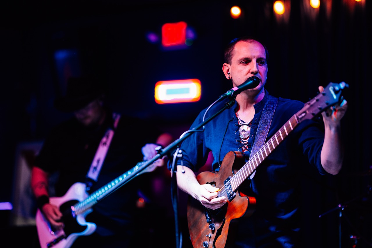 a man playing a guitar in front of a microphone