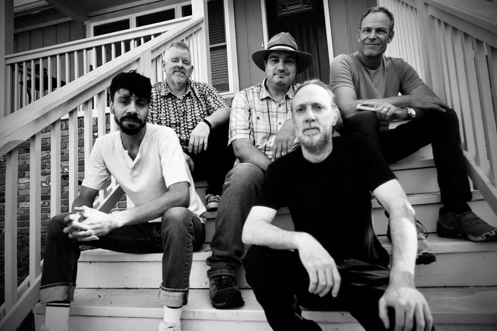 a black and white photo of a group of men sitting on steps