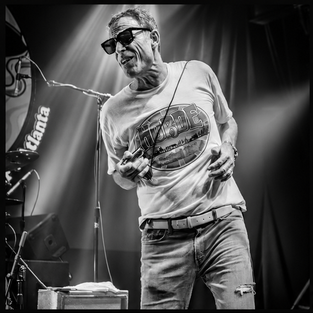 a man in sunglasses on stage with a microphone