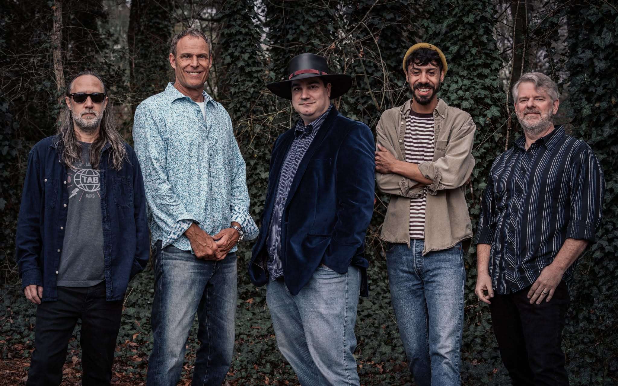 a group of men posing for a picture in the woods