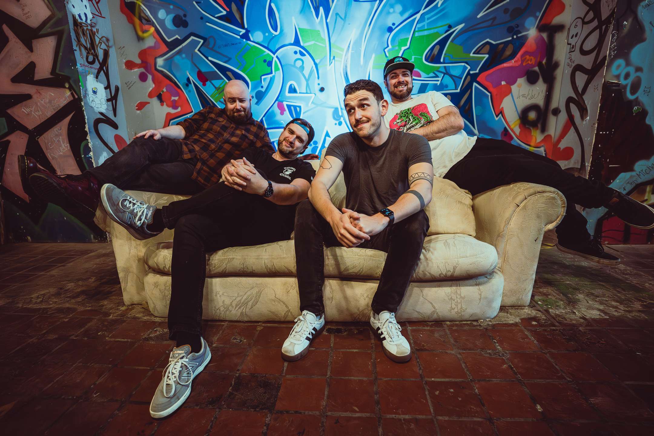 a group of men sitting on a couch in front of graffiti