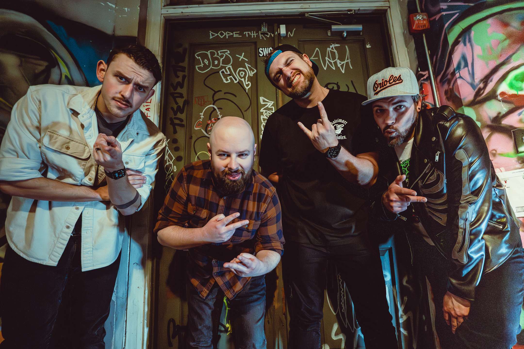 a group of men posing in front of a graffiti covered door