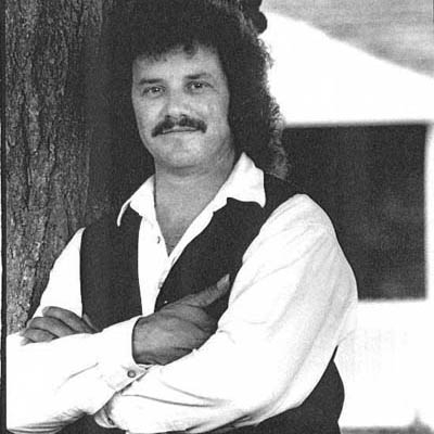 a black and white photo of a man leaning against a tree
