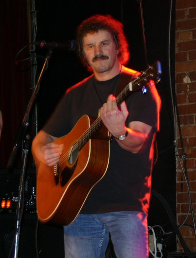 a man with a mustache playing an acoustic guitar