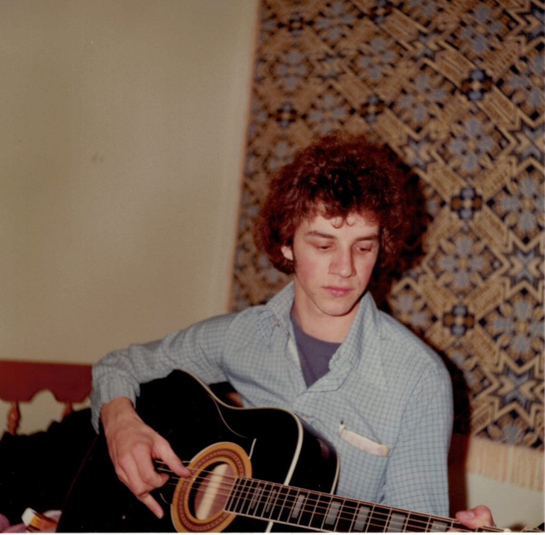a young man playing an acoustic guitar