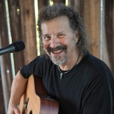 a man smiling while holding an acoustic guitar