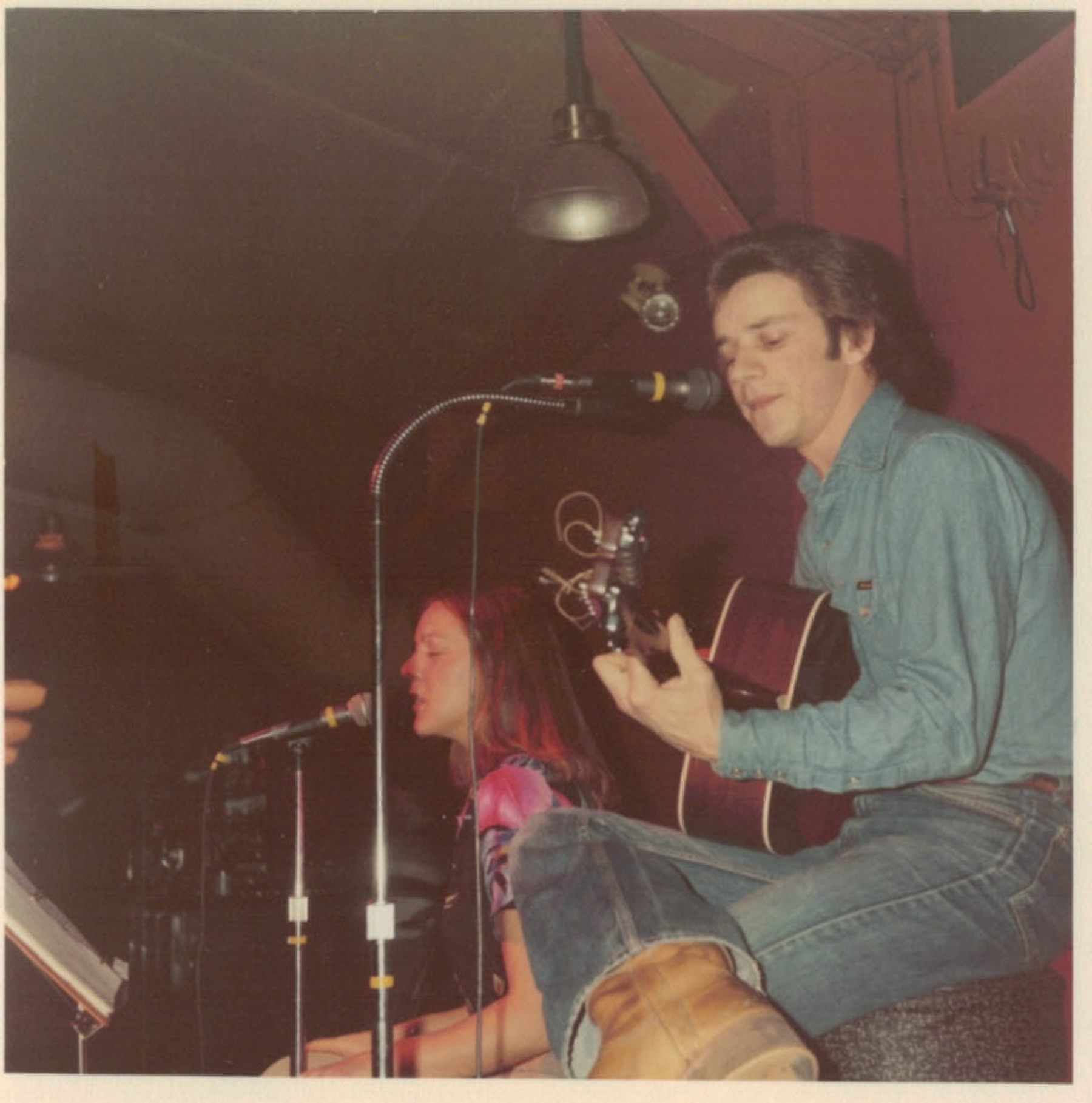 a man and a woman singing and playing an acoustic guitar