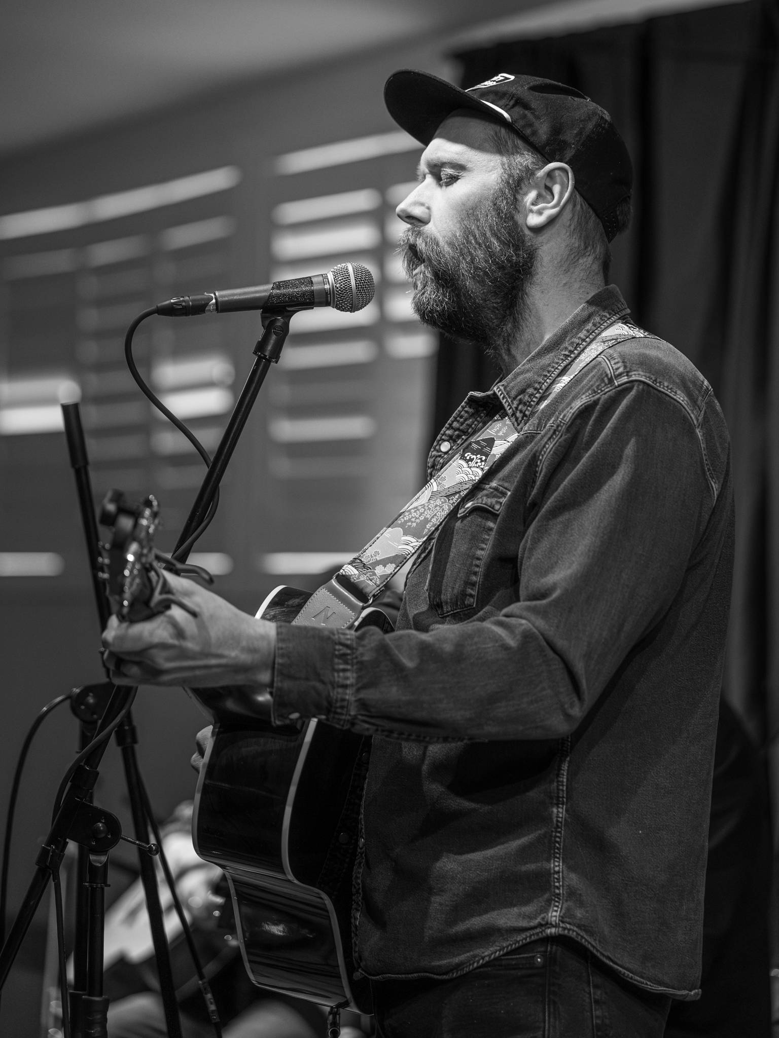a man playing an acoustic guitar in front of a microphone