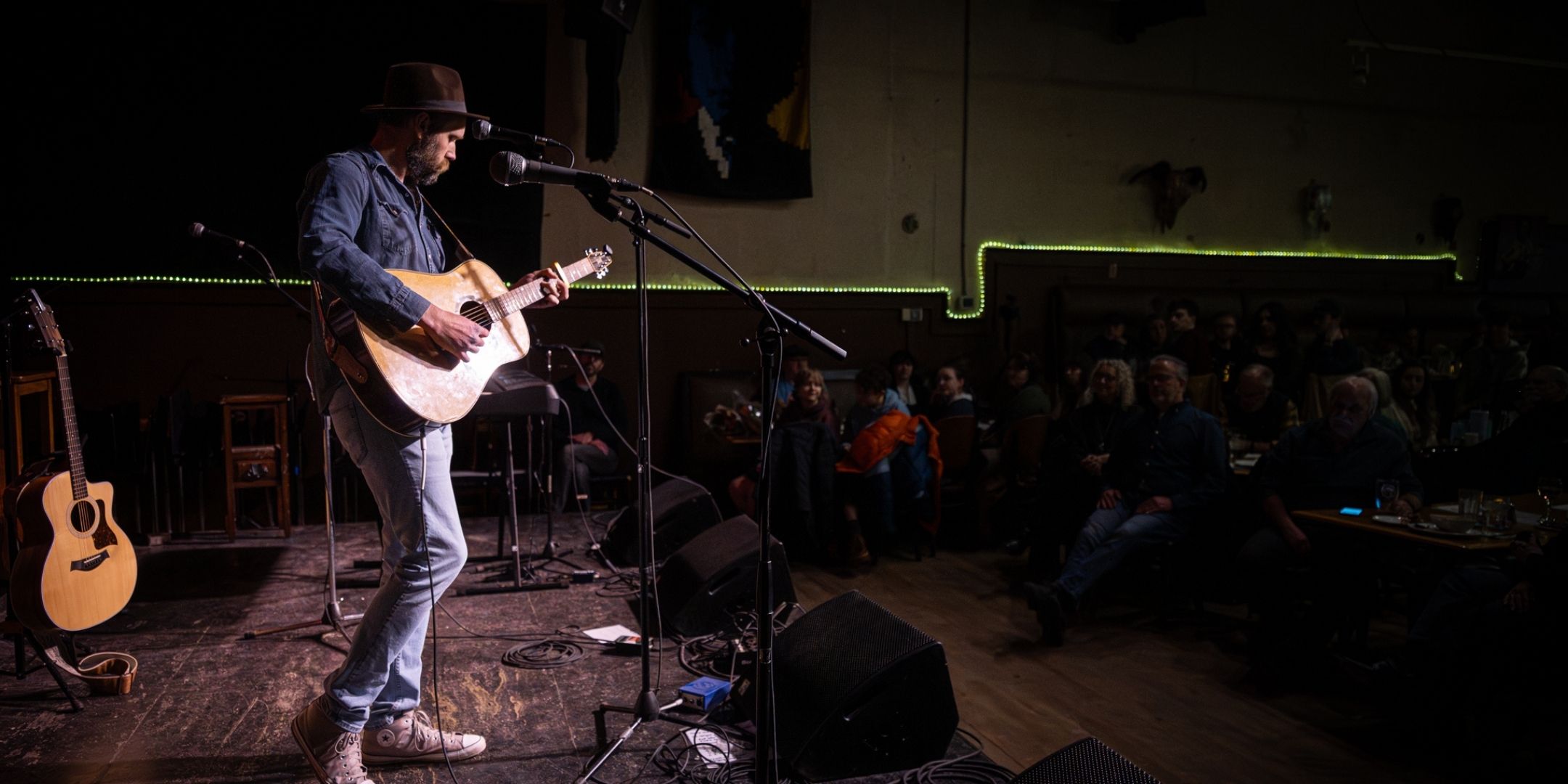 a man playing an acoustic guitar in front of a crowd