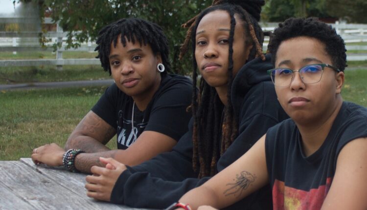 three young black women sitting at a picnic table