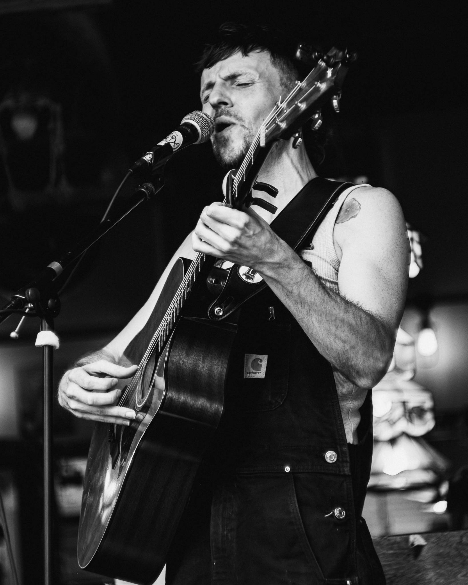 a man playing an acoustic guitar in front of a microphone