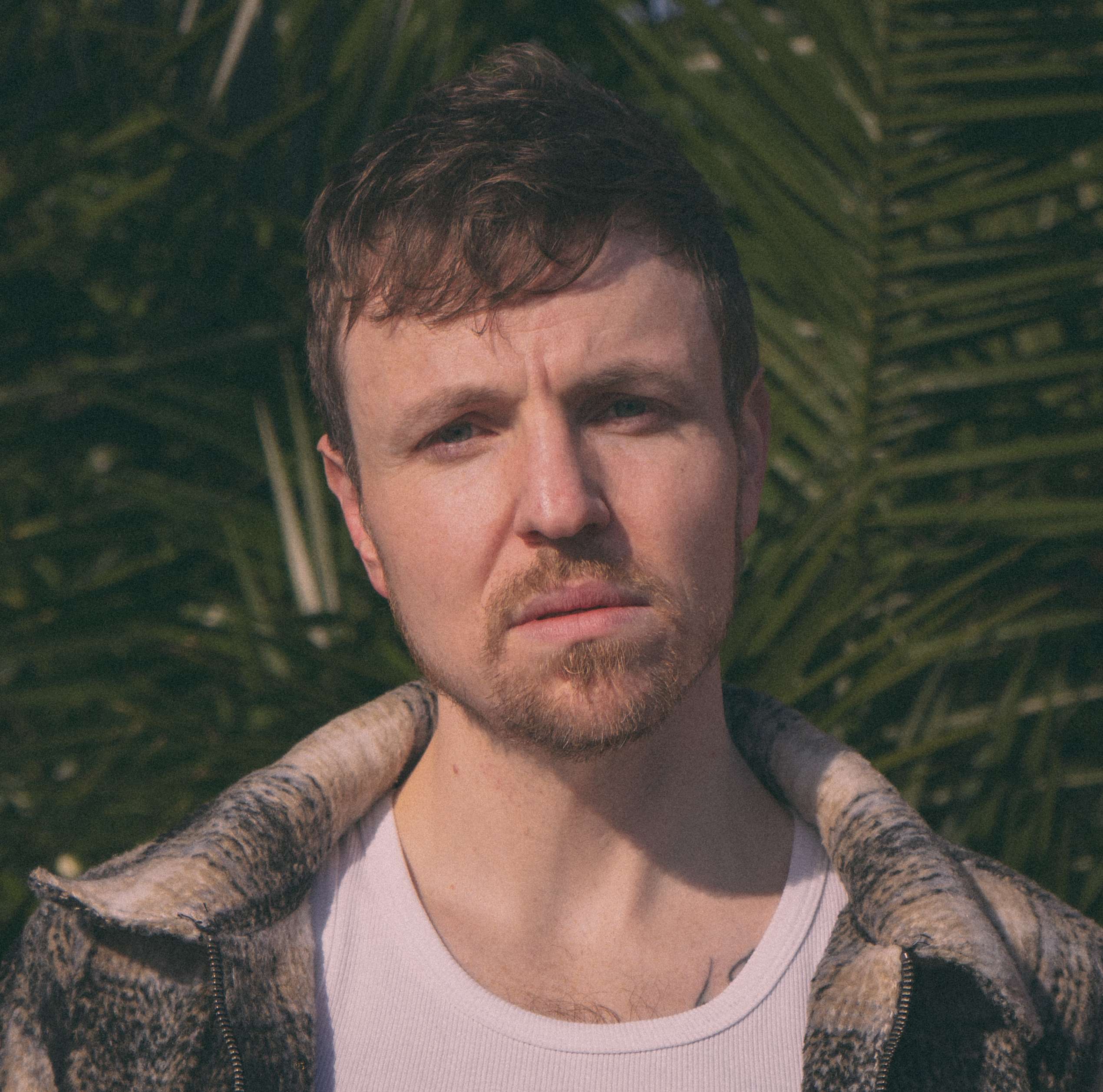 a man is standing in front of a palm tree