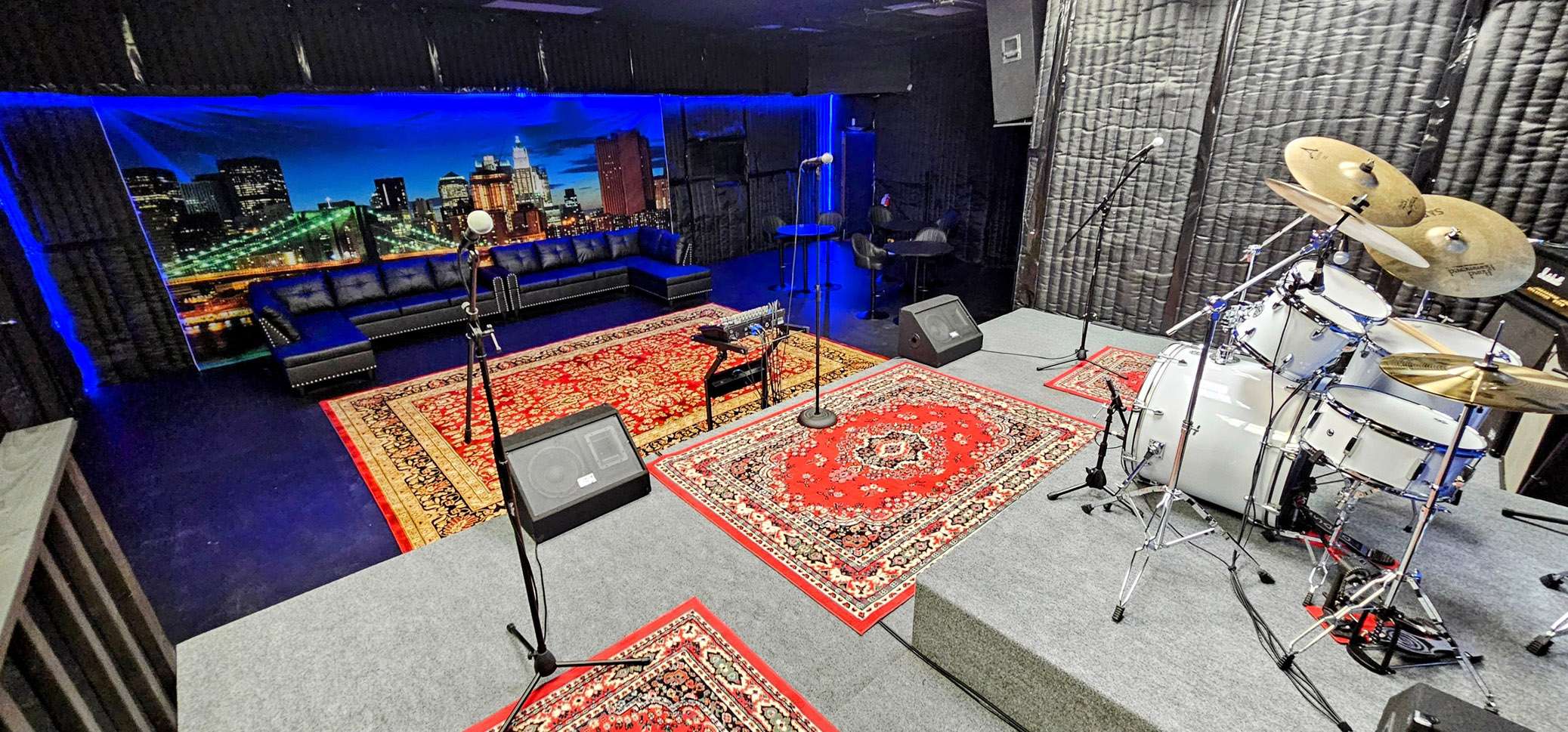 a recording studio with a drum set and a rug