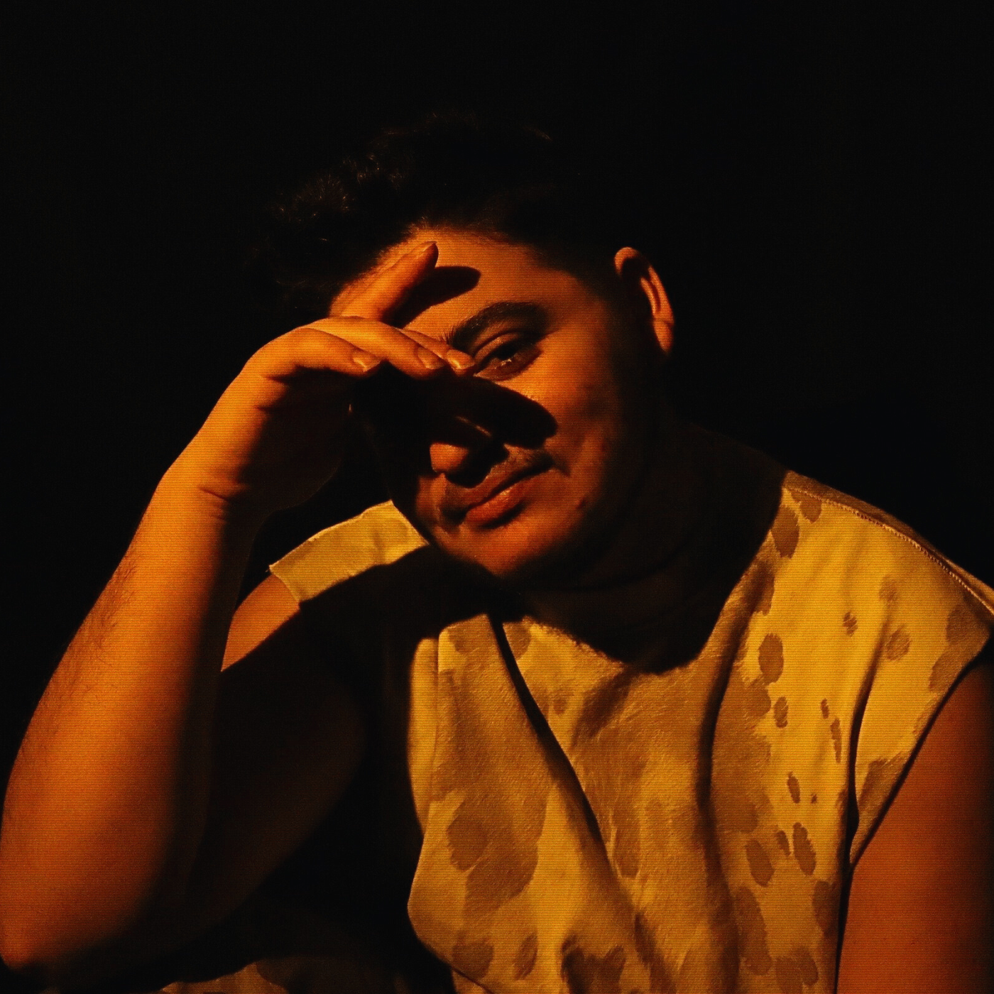 a man in a camouflage shirt with his hand on his face