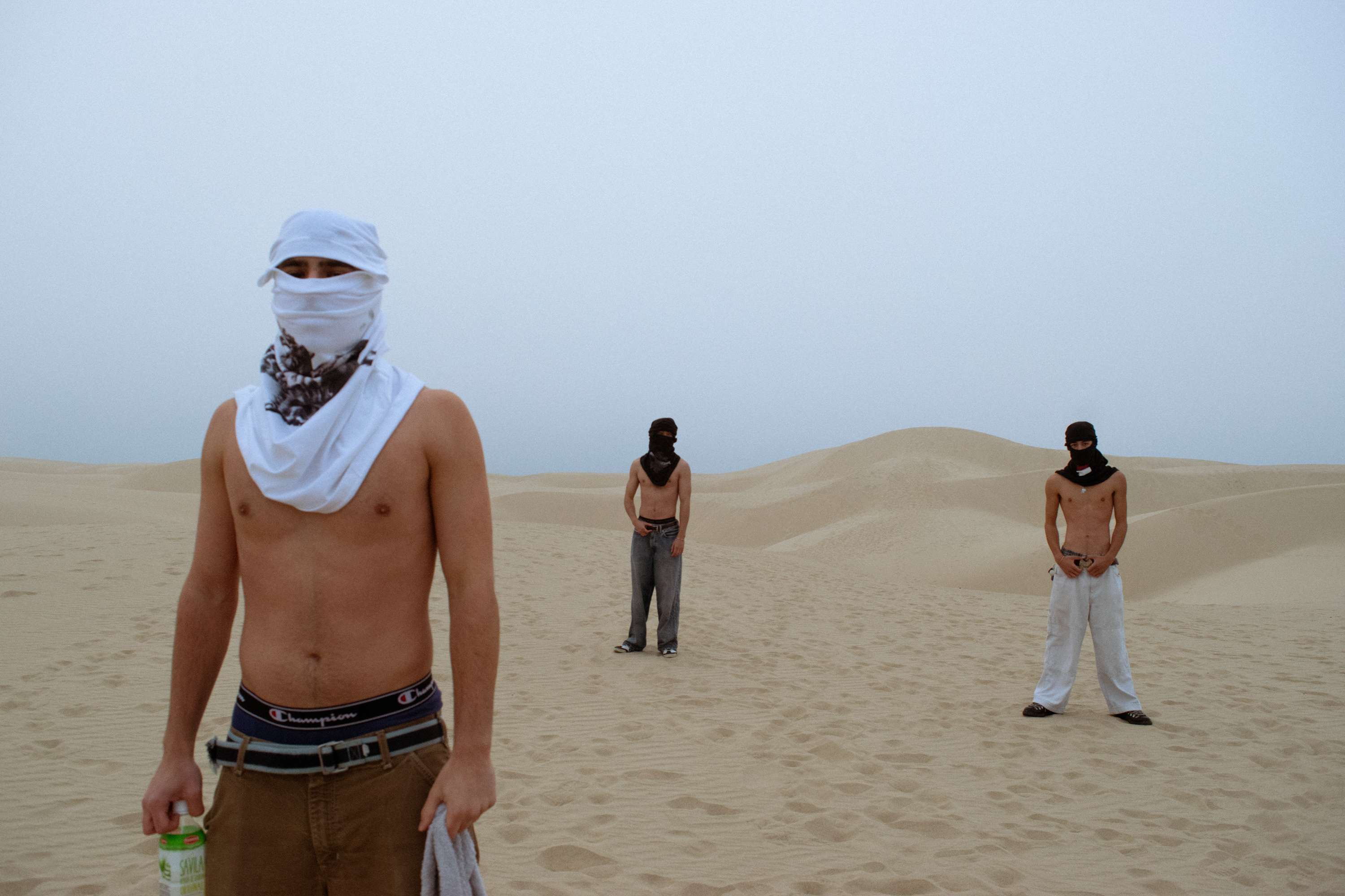 a group of men in a sand dune with masks on