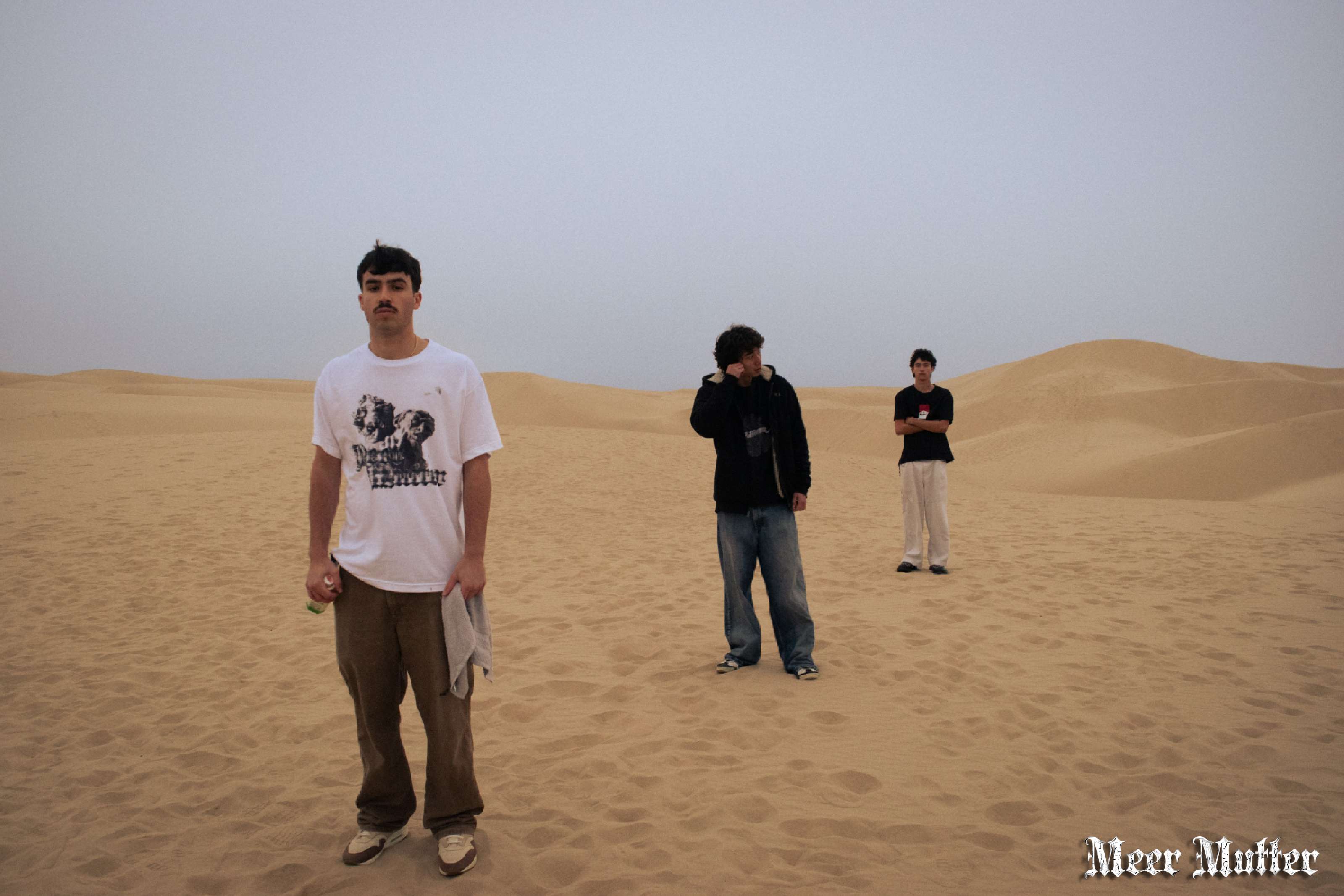 three men standing in the sand in a desert