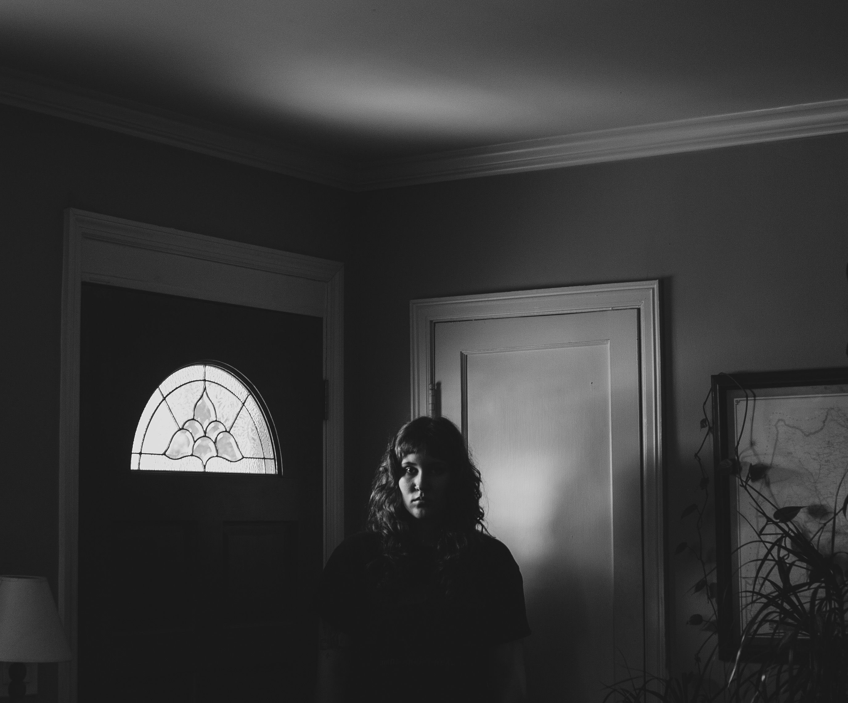 a black and white photo of a woman standing in front of a door