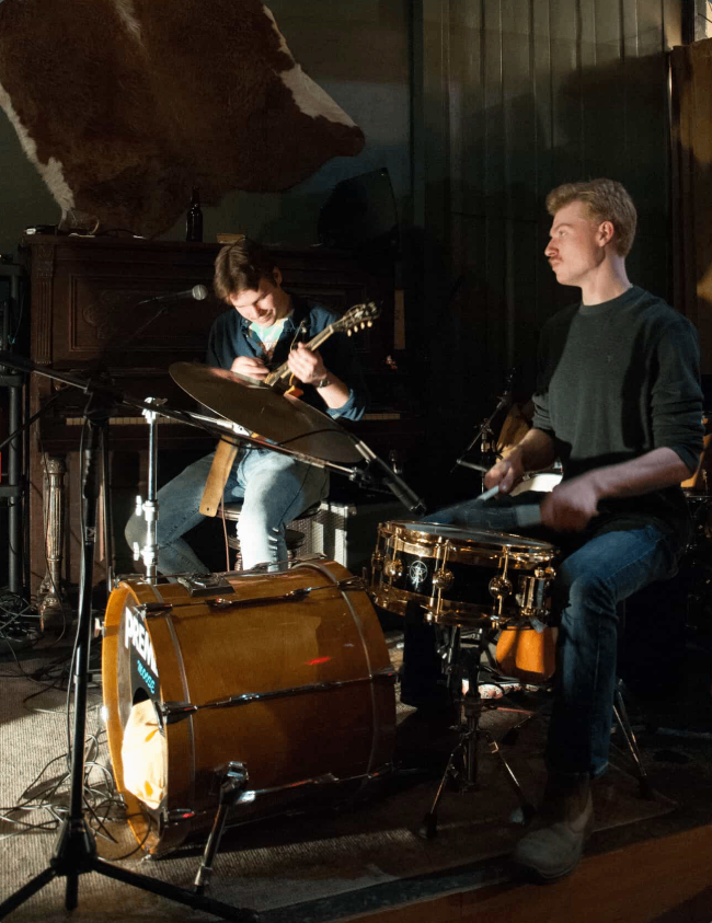two young men playing drums in a room