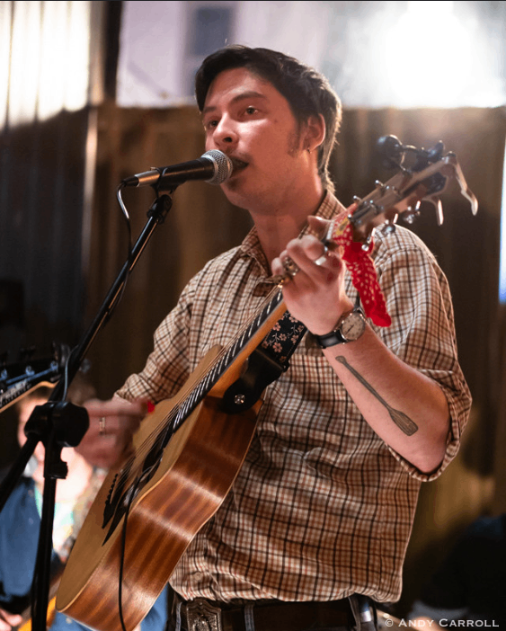 a man singing into a microphone while playing an acoustic guitar