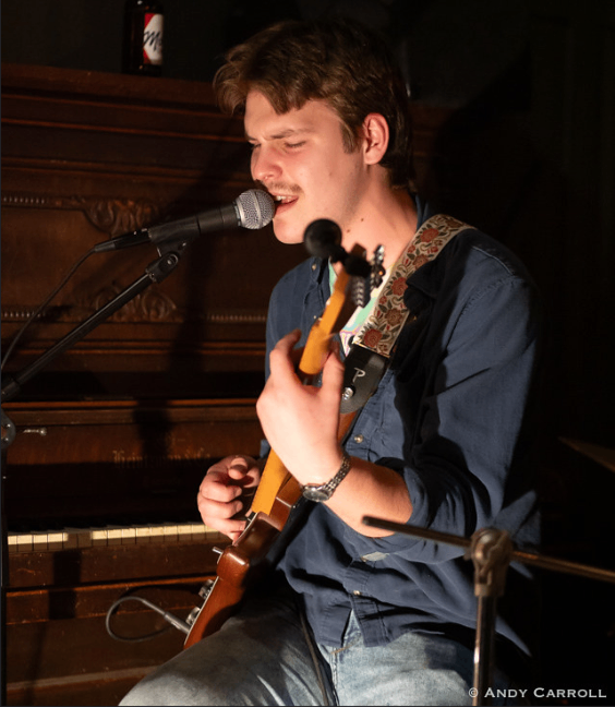 a man playing a guitar in front of a microphone