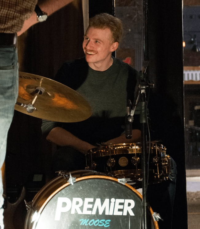 a young man playing drums in front of a bar