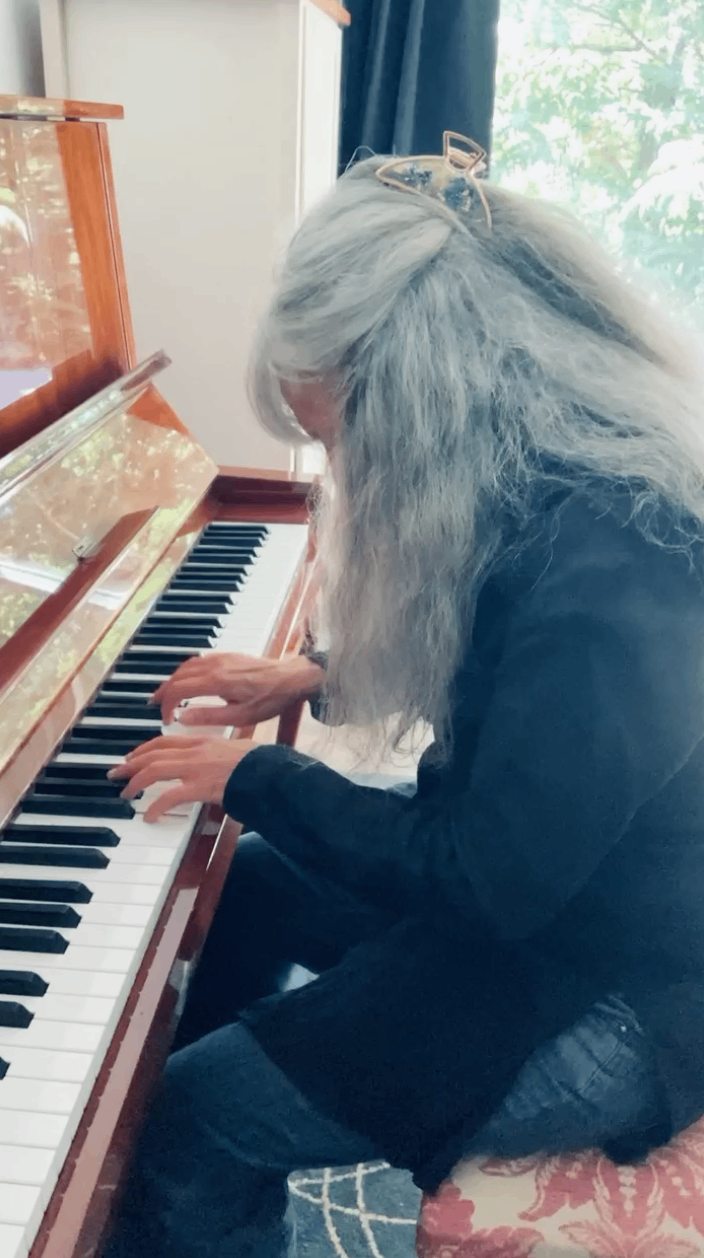 a woman with long hair playing a piano