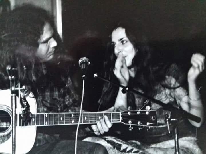 an old photo of a man and woman playing an acoustic guitar