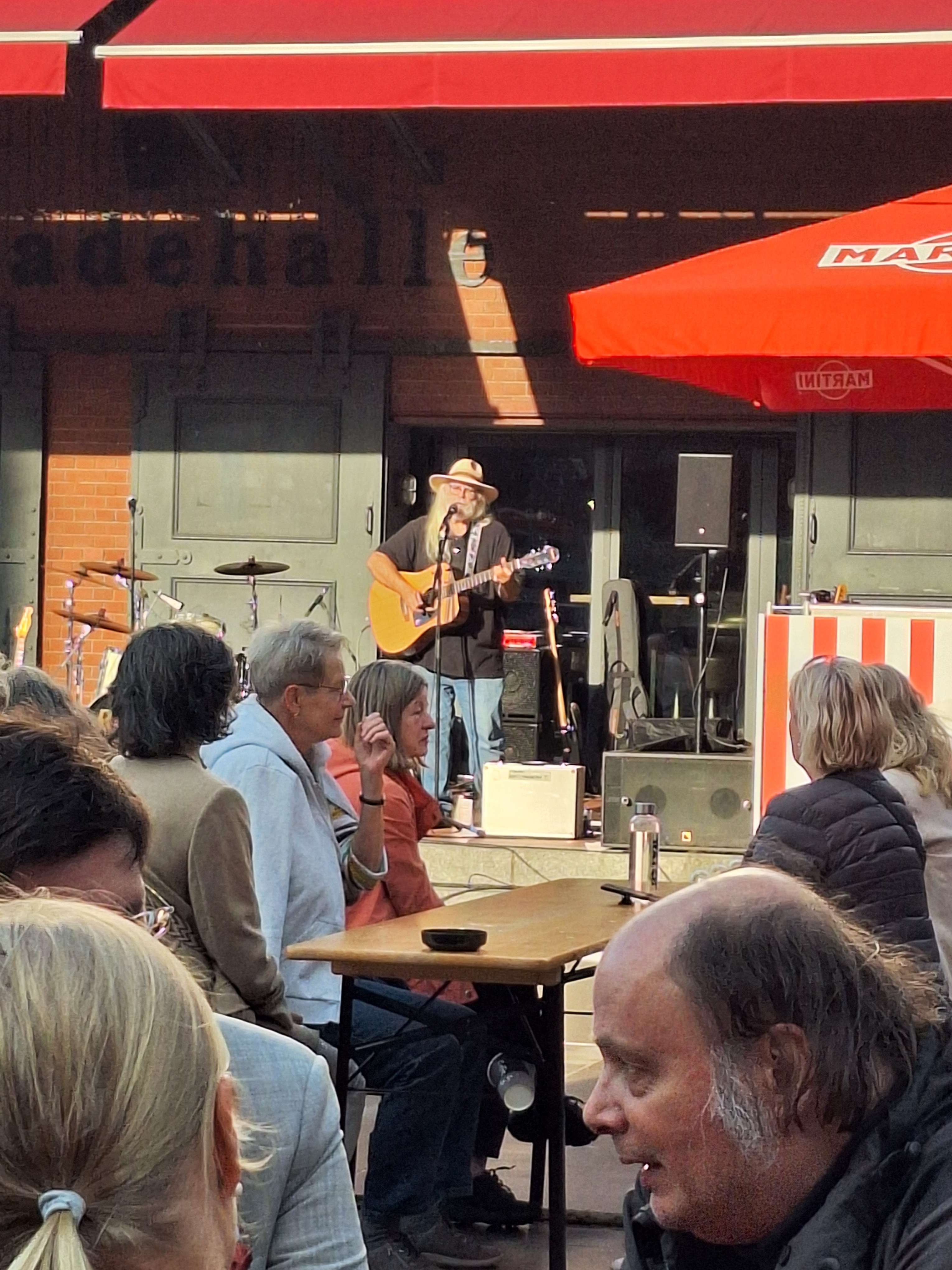 a group of people sitting at a table with a man playing a guitar