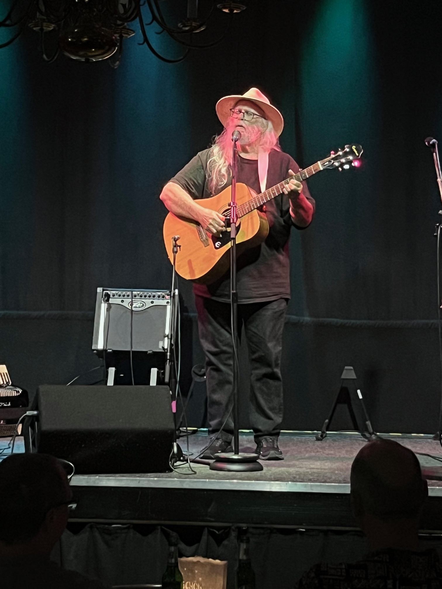 a man in a hat playing an acoustic guitar on stage